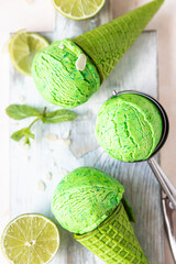 Homemade green ice cream with lime and mint in green waffle cone. Summer dessert. Top view.
