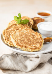 Tasty oatmeal pancakes served with jam and natural yogurt on ceramic plate, light concrete background.