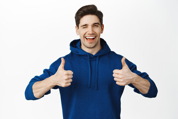 Good job. Smiling supportive boyfriend showing thumbs up and looking pleased. Guy approve smth,...