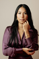 studio portrait of young latina woman posing with gold jewelry. elegant girl looking at camera.