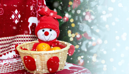 Decorative basket with christmas gifts. Funny and cute christmas Snowman with tangerines and new year decor on background Christmas plaid  and Christmas tree.Close up. Copy space