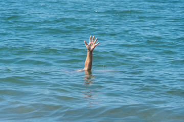 One hand of a drowning man in the sea, asking for help on a sunny day
