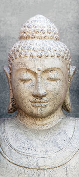 Buddha head in stone on a plain background, bust of religion