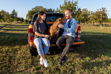 Fototapeta premium Cute couple and their faithful canine bully friend spending time together on a beautiful day out