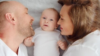 Happy parents with his newborn baby, top view. Happy family. Healthy newborn baby with mom and dad. Close up Faces of the mother, father and infant baby. Cute Infant boy and parents.