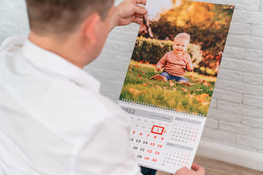 man holds a calendar with a photo of a child. printed products.