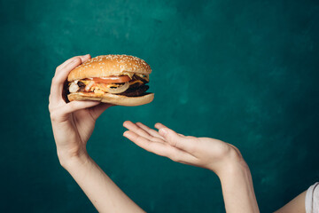 hamburger in hands close-up fast food green background