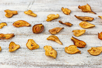 A pile of dried pears in slices on a white wooden background. Dried fruit chips. Healthy food