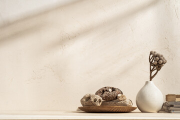 Dried branch in the vase and books near bright cement wall.