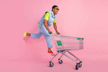 Full body profile photo of cool young brunet guy run do shopping wear eyewear t-shirt vest jeans sneakers isolated pink background © deagreez