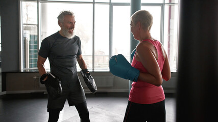 Older man and woman boxing in gym