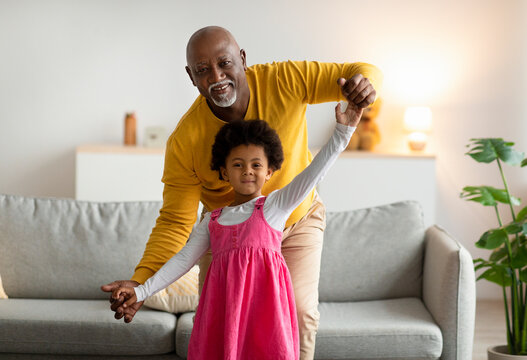 Smiling african american little girl and old man dancing and have fun