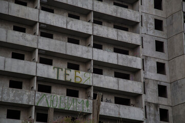 VLADIVOSTOK, RUSSIA - 03/09/2021  close up of a soviet empty abandoned unfinished haunted residential concrete panel house building with balconies and a writing WE LOVE YOU in Russian