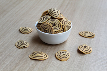 Kue Kuping Gajah, traditional cookies from Indonesia. Sweet and crunchy, unique spiral pattern. Wooden background.