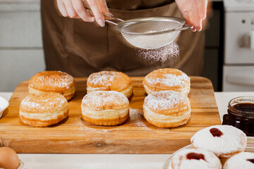 Woman chef prepares fresh donuts in her bakery. Cooking traditional Jewish Hanukkah Sufganiyot....