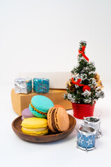 Arrangement of French cookies, artificial Christmas tree and gifts.