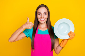 Photo of nice lady hold white plate raise thumb up wear latex gloves pink apron isolated yellow color background