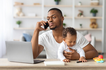 Busy Black Man Working Remotely At Home With Little Baby On Hands