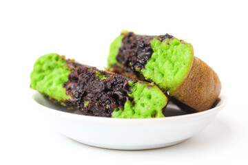 Green colored pukis with melted chocolate topping. Pukis is an Indonesian traditional sweet pancake. On a small white plate. Isolated on white background
