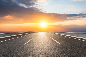 Asphalt road and sea scenery at sunrise, road and sky background.