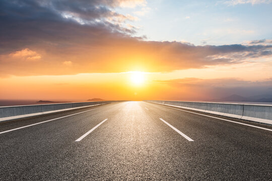 Asphalt road and sea scenery at sunrise, road and sky background.