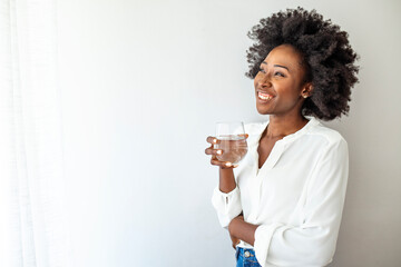Happy beautiful young woman holding drinking water glass in her hand. Health care concept. Young...