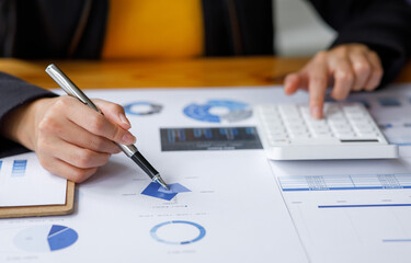 Close up a Business woman using calculator and laptop for doing math finance on a wooden desk, tax, accounting, statistics, and analytical research concept