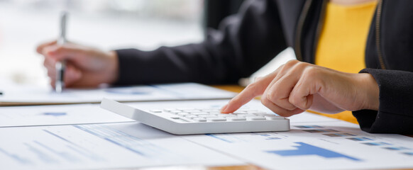 Close up a Business woman using calculator and laptop for doing math finance on a wooden desk, tax,...
