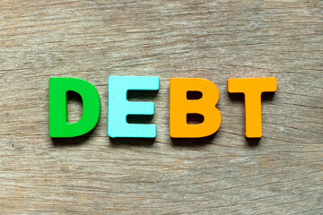 Color alphabet letter in word debt on wood background