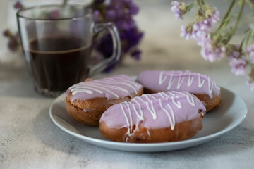 Blueberry eclairs on a gray plate and a glass cup of coffee on a gray cement background.