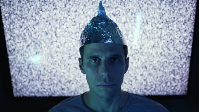 Man wearing tin foil hat in a front of TV