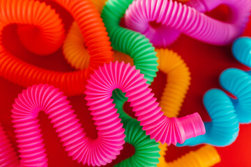 Colorful anti-stress fidget pop tube sensory toy on red background. Flat lay.
