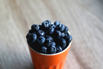 Cup of fresh blueberries on wooden table. Selective focus.