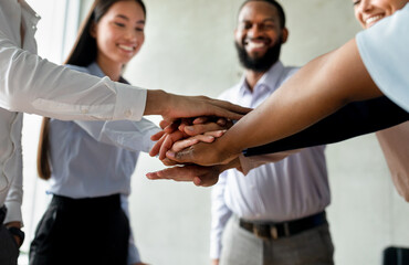 Fototapeta premium Corporate Traditions. Group Of Happy Multiethnic Collagues Stacking Hands Together