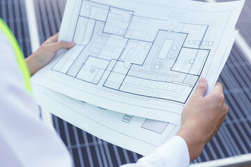 Engineer open blueprint of solar farm project on solar cells panel