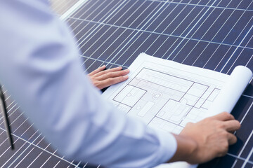 Engineer open blueprint of solar farm project on solar cells panel