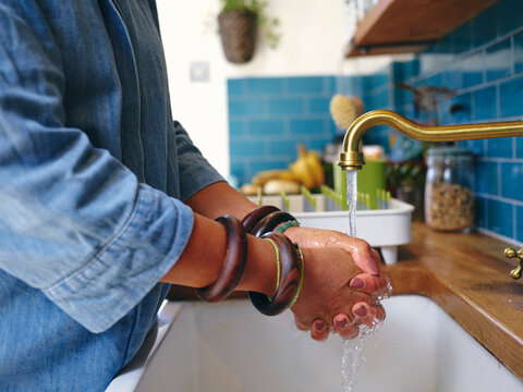 Woman washing hands in kitchen, close-up