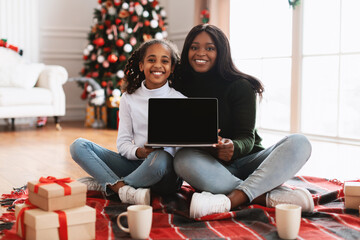 Happy black family showing pc with empty screen, mockup
