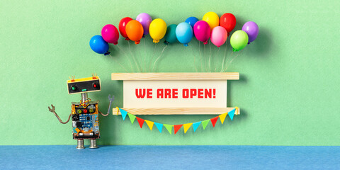 We are open. Invitation greeting card for opening ceremony, start of a project, business launch. Robot and wooden sign decorated with balloons, garland of flags. purple violet background. - 471302110