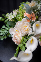 Plastic handmade bouquet artificial flowers composition.Beautiful flowers in vase on a table with black  background. Women's, mother's day. Spring, summer season. Front view.Selective focus.
