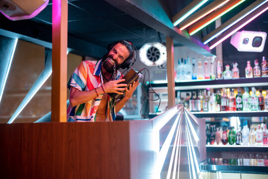 Cheerful DJ having fun during party in modern bar