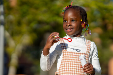 Positive black child blowing soap bubbles in nature