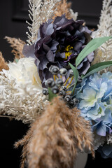 Plastic handmade bouquet artificial flowers composition.Beautiful flowers in vase on a table with black  background. Women's, mother's day. Spring, summer season. Front view.Selective focus.
