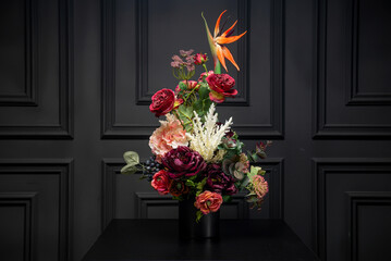 Plastic handmade bouquet artificial flowers composition.Beautiful flowers in vase on a table with black  background. Women's, mother's day. Spring, summer season. Front view.Selective focus.
