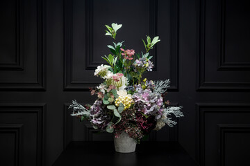 Plastic handmade bouquet artificial flowers composition.Beautiful flowers in vase on a table with black  background. Women's, mother's day. Spring, summer season. Front view.Selective focus.

