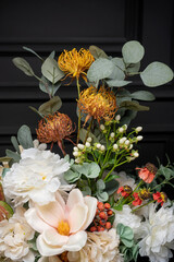 Plastic handmade bouquet artificial flowers composition.Beautiful flowers in vase on a table with black  background. Women's, mother's day. Spring, summer season. Front view.Selective focus.
