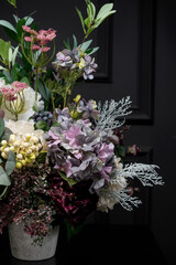 Plastic handmade bouquet artificial flowers composition.Beautiful flowers in vase on a table with black  background. Women's, mother's day. Spring, summer season. Front view.Selective focus.
