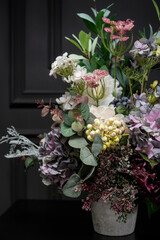 Plastic handmade bouquet artificial flowers composition.Beautiful flowers in vase on a table with black  background. Women's, mother's day. Spring, summer season. Front view.Selective focus.
