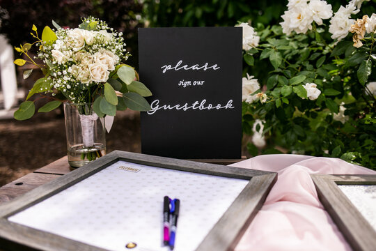 black sign with words please sign our guestbook and frame with place for wedding guests to sign