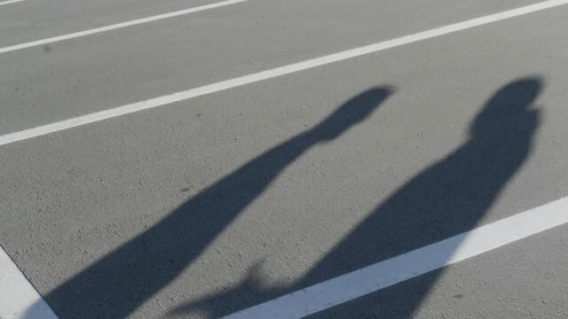 The silhouettes of two young men during angry conflict. HDR. Shadows of arguing friends with each other on the background of parking asphalt.